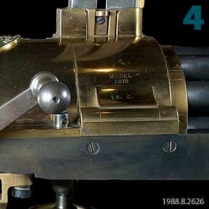 Close-up of the U.S. Model 1875 Gatling Gun, a significant piece of military history, showcasing its detailed mechanics and brass finish.