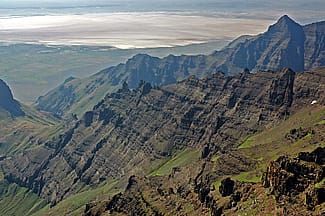 Steens Mountain escarpment of eastern Oregon, looking east into the Alvord basin. The escarpment is composed of thin lava flows cut by vertical dikes that feed the initial eruptions of the Columbia River flood basalts. These 17-million-year-old basalts represent the first direct manifestation of the Yellowstone hotspot.”