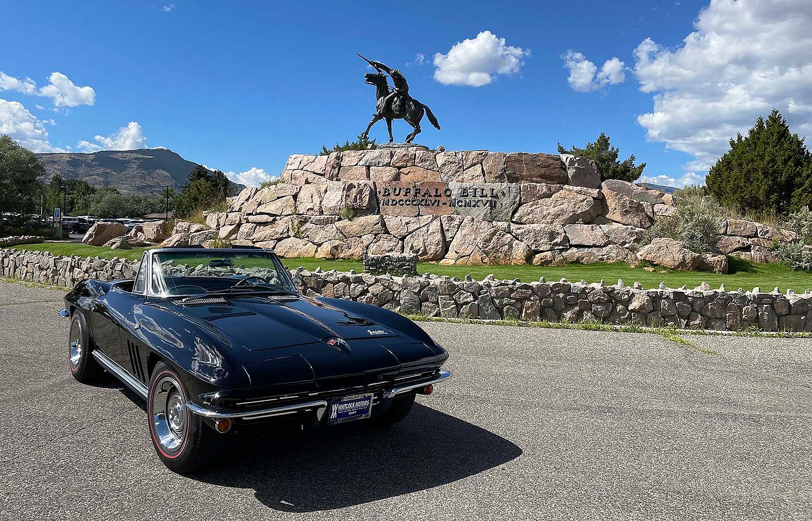 Black, 1966 Corvette convertible raffle car parked in front of Buffalo Bill - The Scout sculpture.