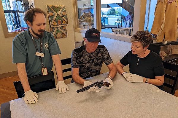 Exclusive Tours guide Nick shows a revolver to two tour participants.