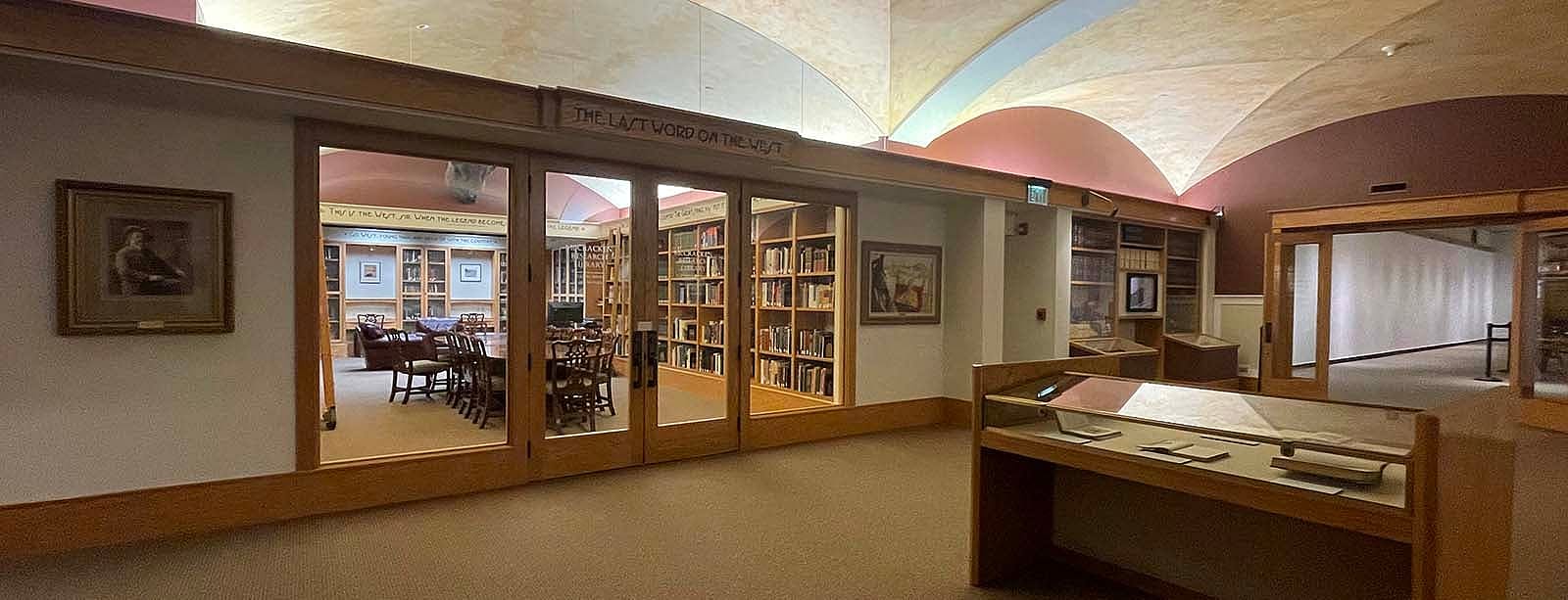 McCracken Research Library, view of display case in lobby; then looking through glass to reading room with book shelves and large table.